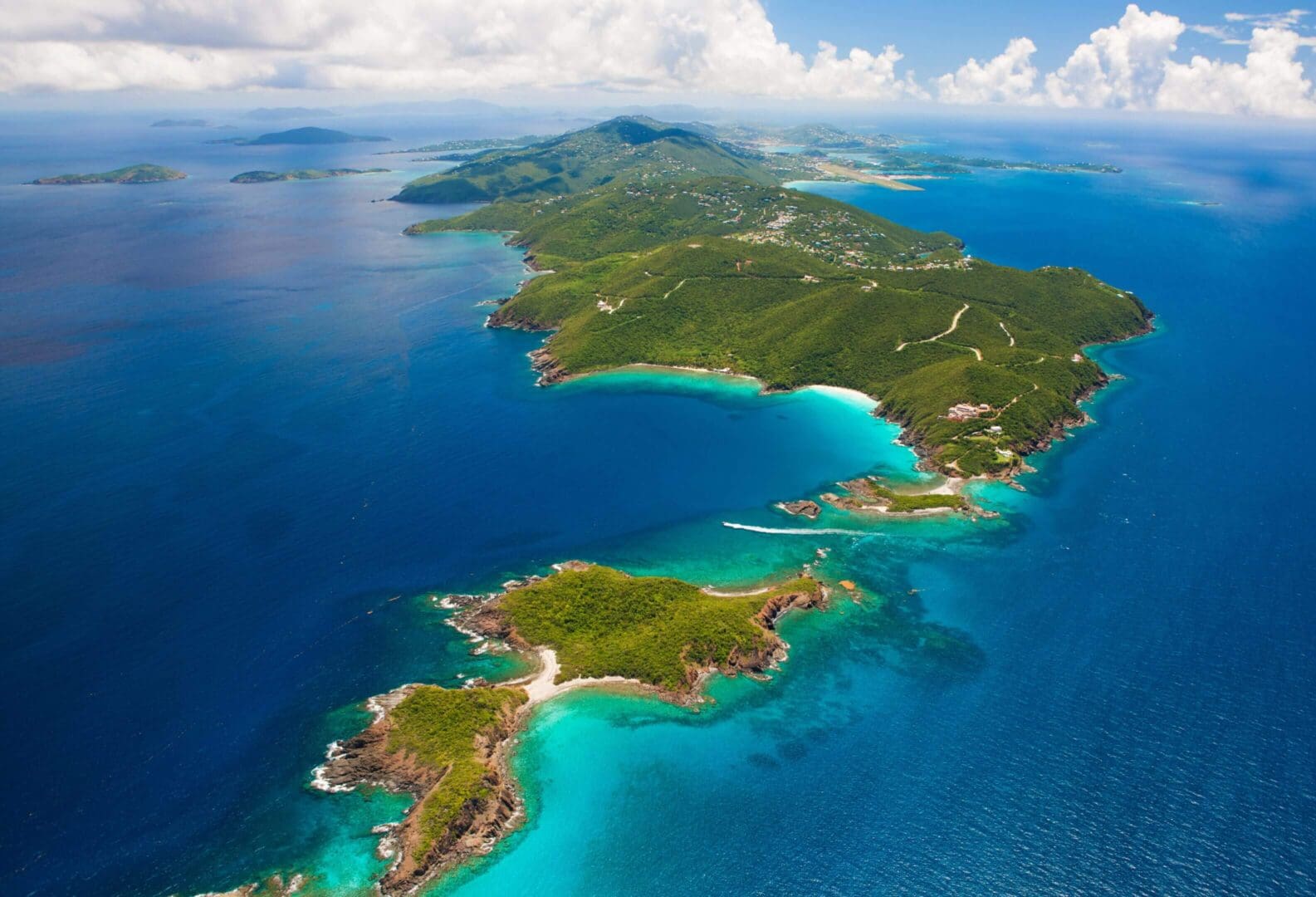 Aerial view of a lush tropical island surrounded by clear blue ocean.
