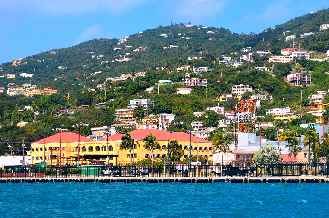Coastal town with colorful buildings and lush green hills.