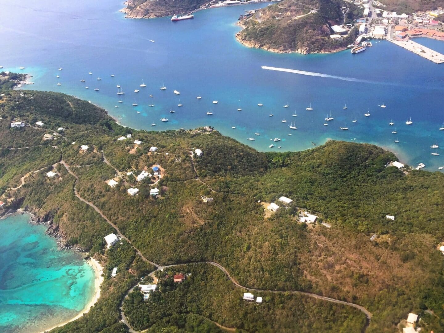 Aerial view of a coastal area with boats and greenery.